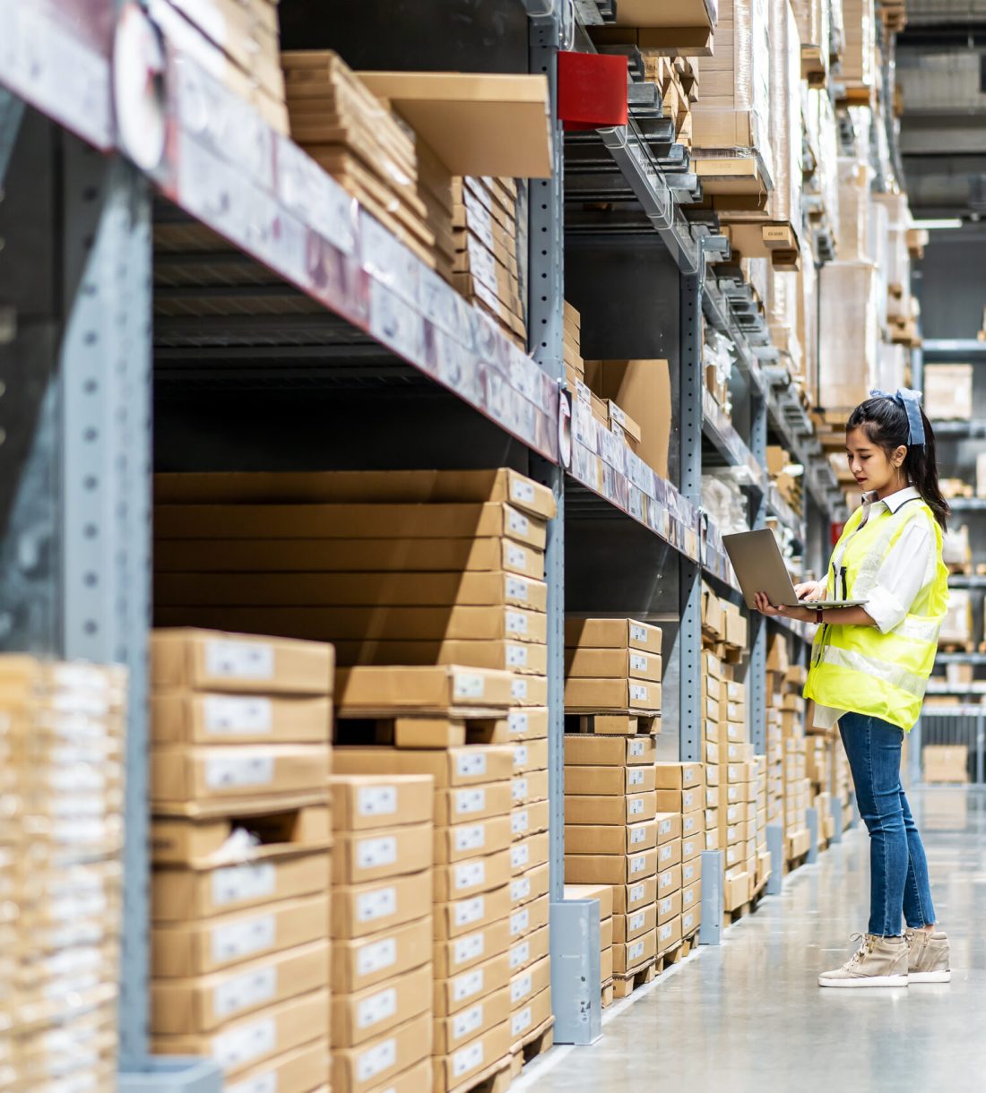 Asian engineer woman check stock details on tablet computer for checking boxes with logistics on shelves with goods background in warehouse